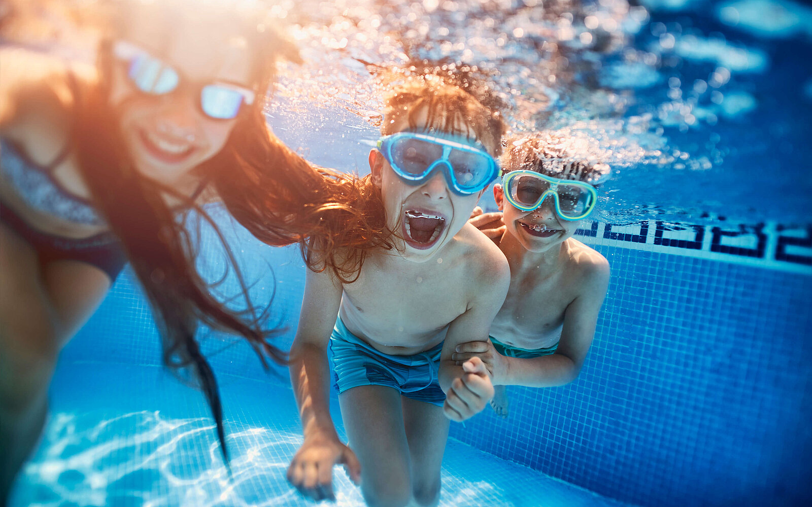 Kinder im Schwimmbad beim tauchen mit Taucherbrille haben Spaß.
